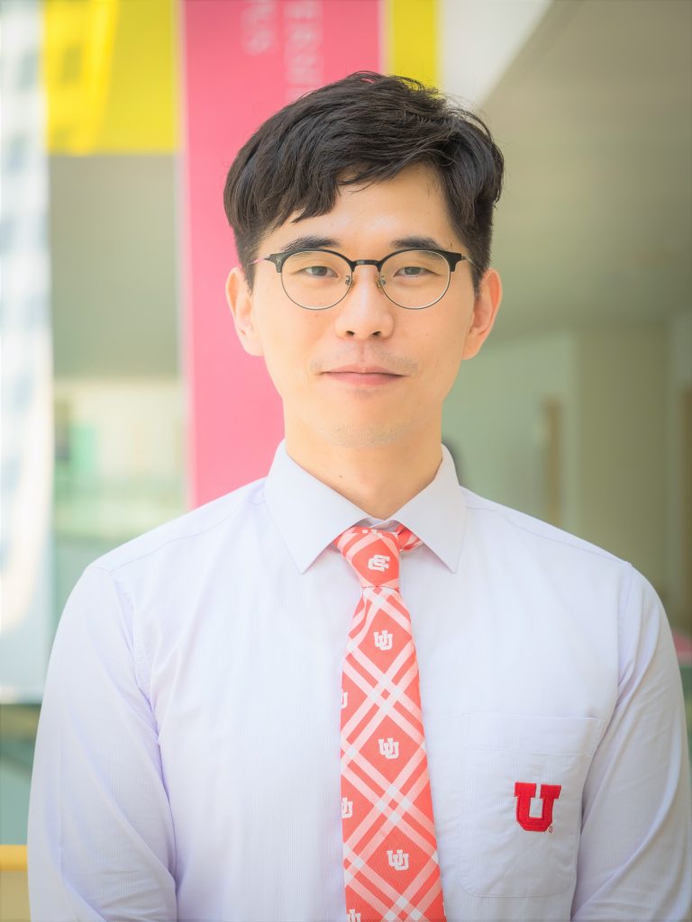 Asian man in white shirt, red plaid tie and glasses.
