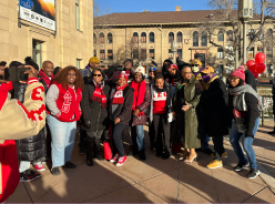 A group of people dressed in black and red pose for a group photo on the U's campus.